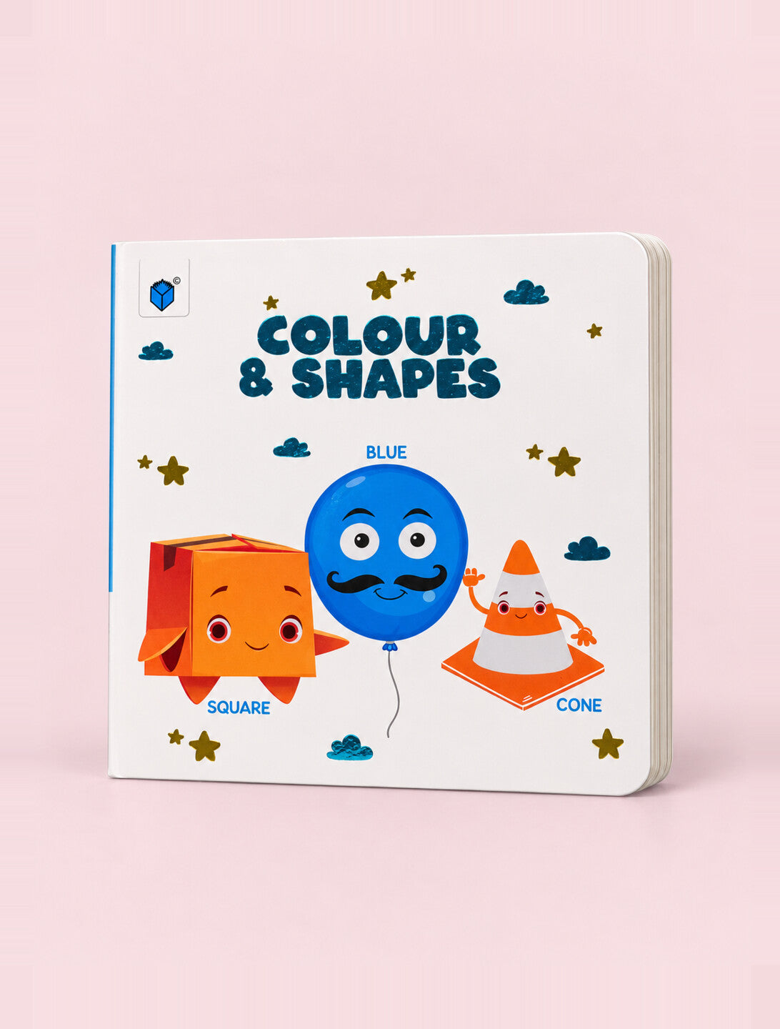 A children's board book titled 'COLOUR & SHAPES' standing upright on a light pink background. The white cover features colorful cartoon illustrations of a blue balloon, an orange square box, and an orange traffic cone, with small gold stars and blue clouds.